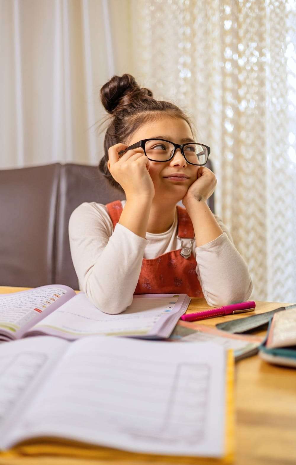 Young student resting her chin on her hand and looking away from her open notebook